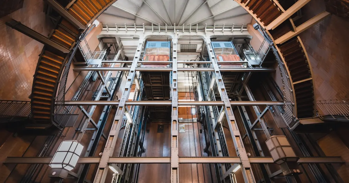 Looking up through a multi-storey elevator shaft with steel guide rails and framework